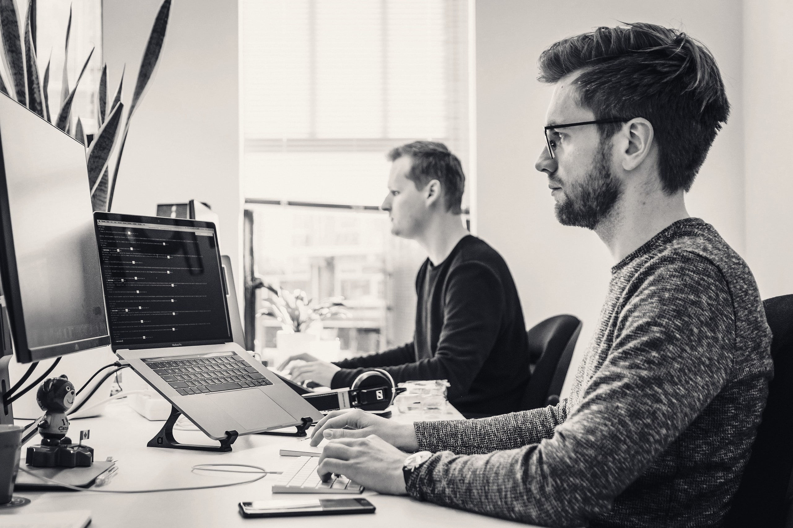 Two developers working at a desk with large monitors