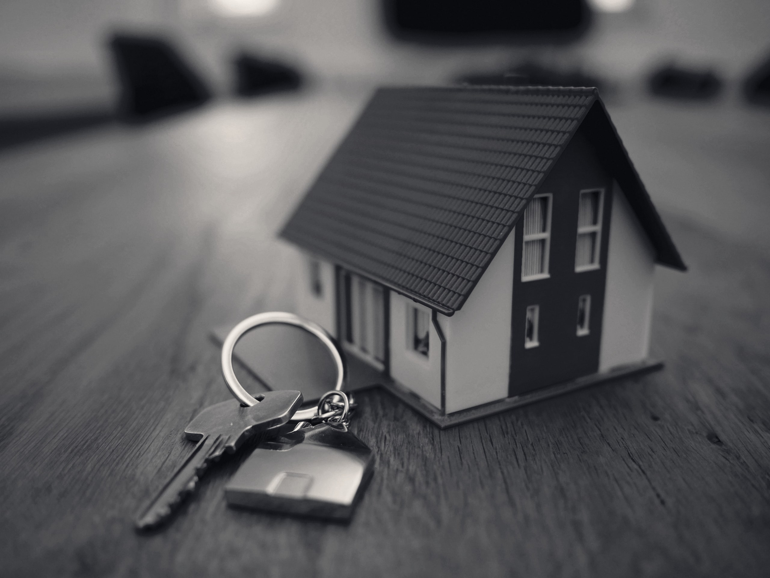 Miniature house with keys on a wooden table
