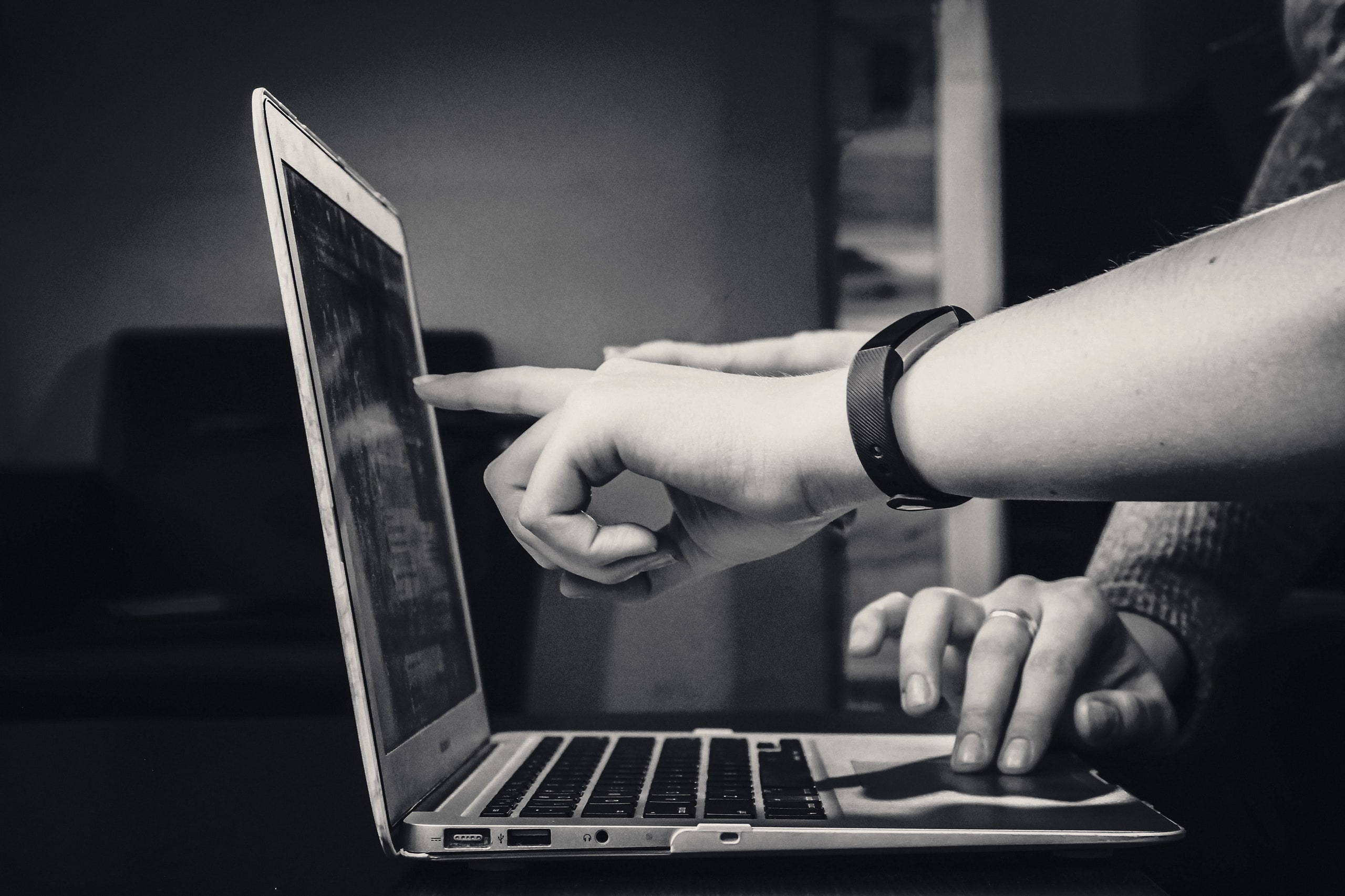Two people pointing at a laptop screen while reviewing a result