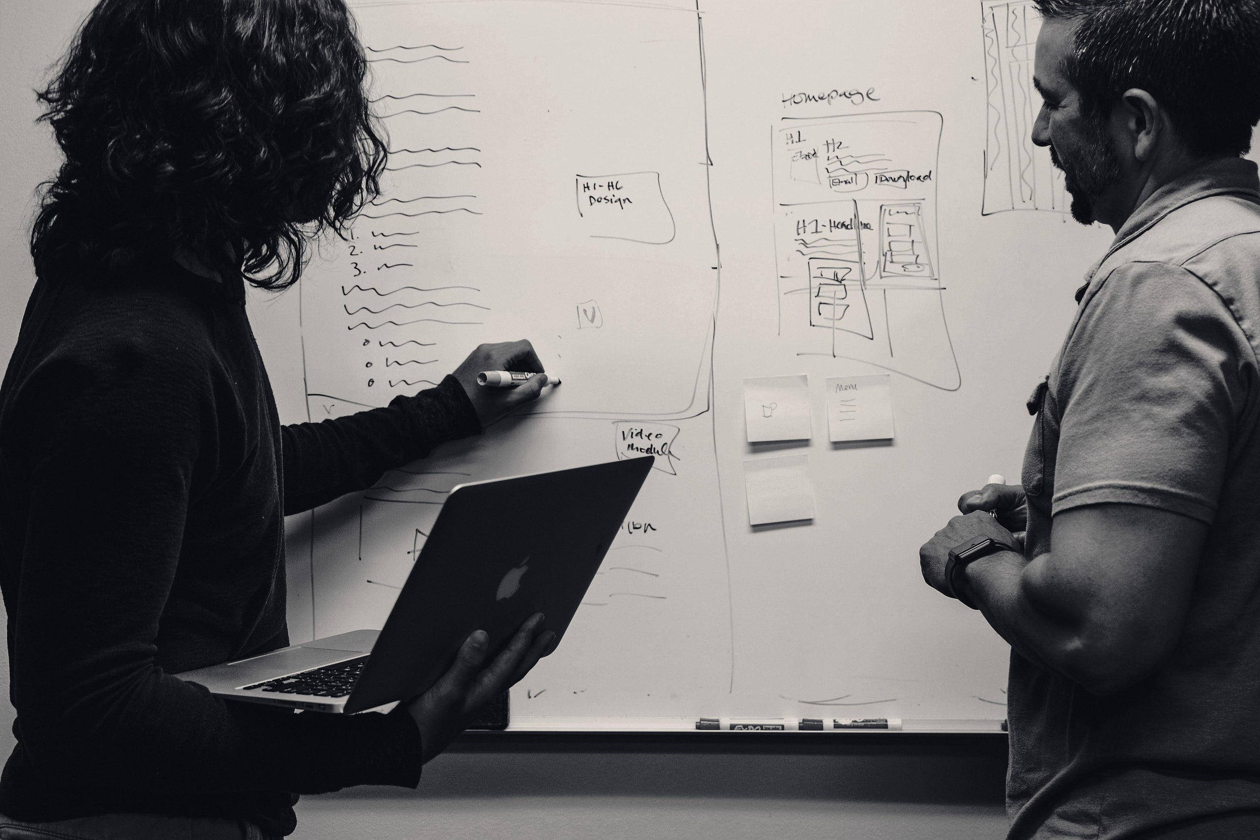 Two colleagues planning at a whiteboard